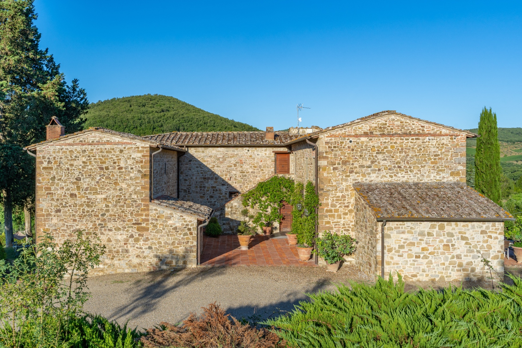 Rimocine farmhouse courtyard with terracotta paving, potted plants and stone façade