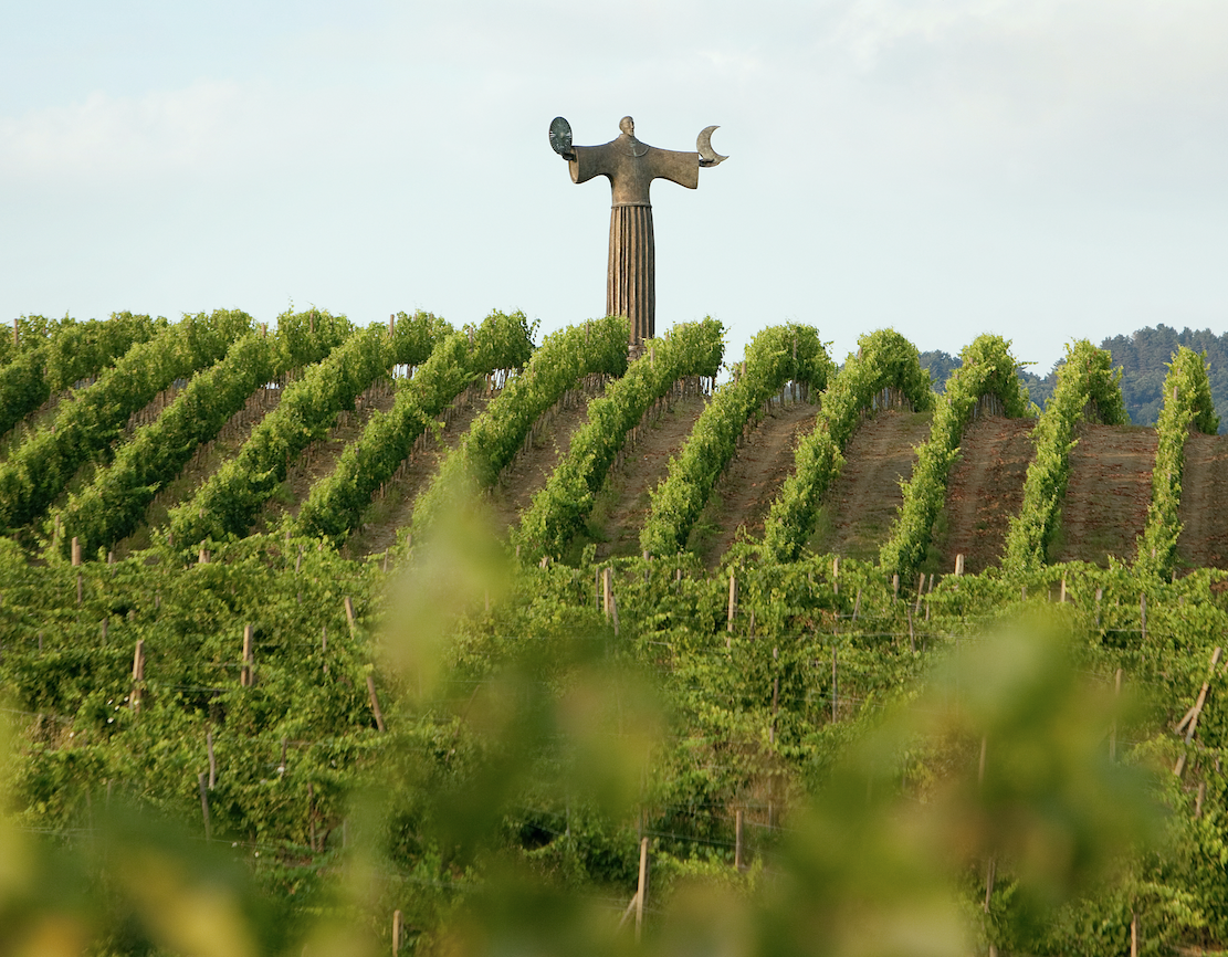 A golden sentinel sculpture on a hill above the vineyards