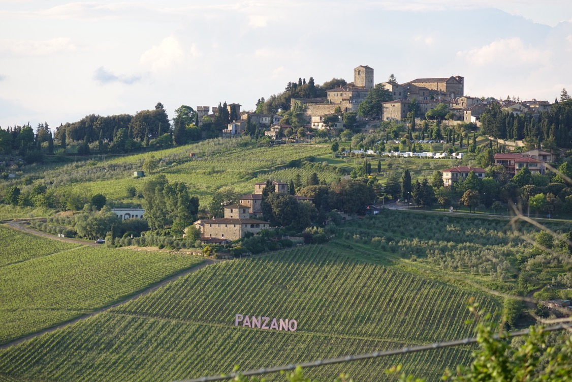 The hilltop village of Panzano-in-Chianti overlooking vineyards with 'PANZANO' lettering in the field