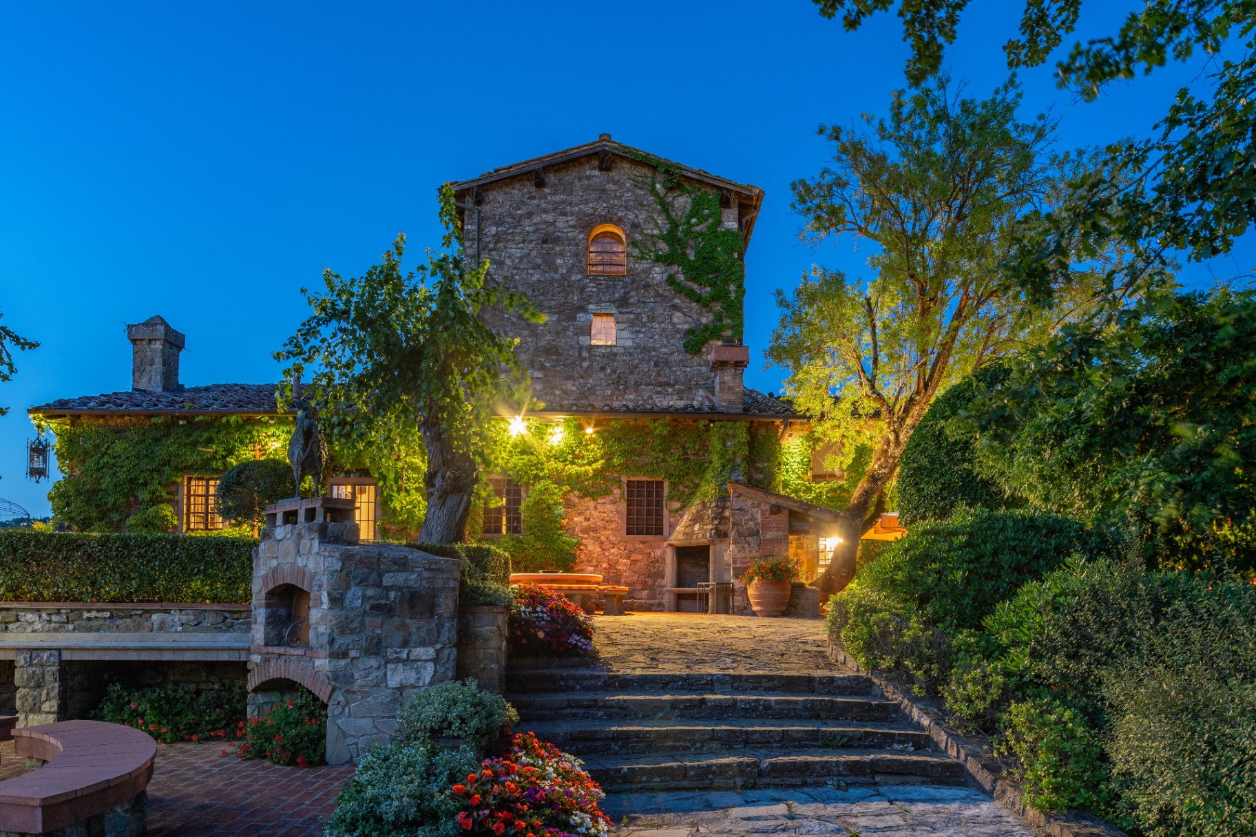 Villa Castagnoli illuminated at dusk, with stone façade, gardens and steps