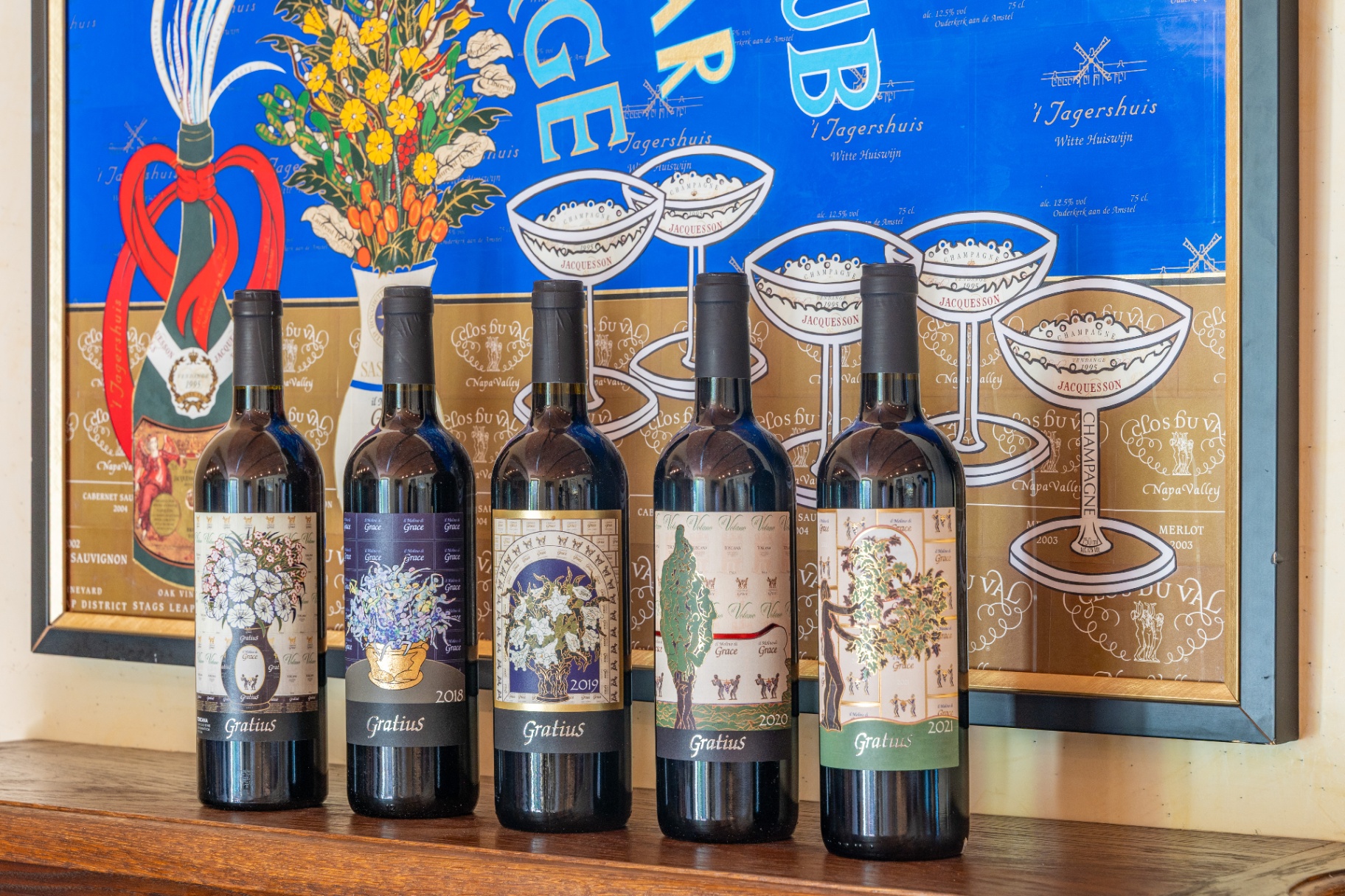 Five vintages of Gratius Super Tuscan bottles displayed in front of an artistic framed backdrop