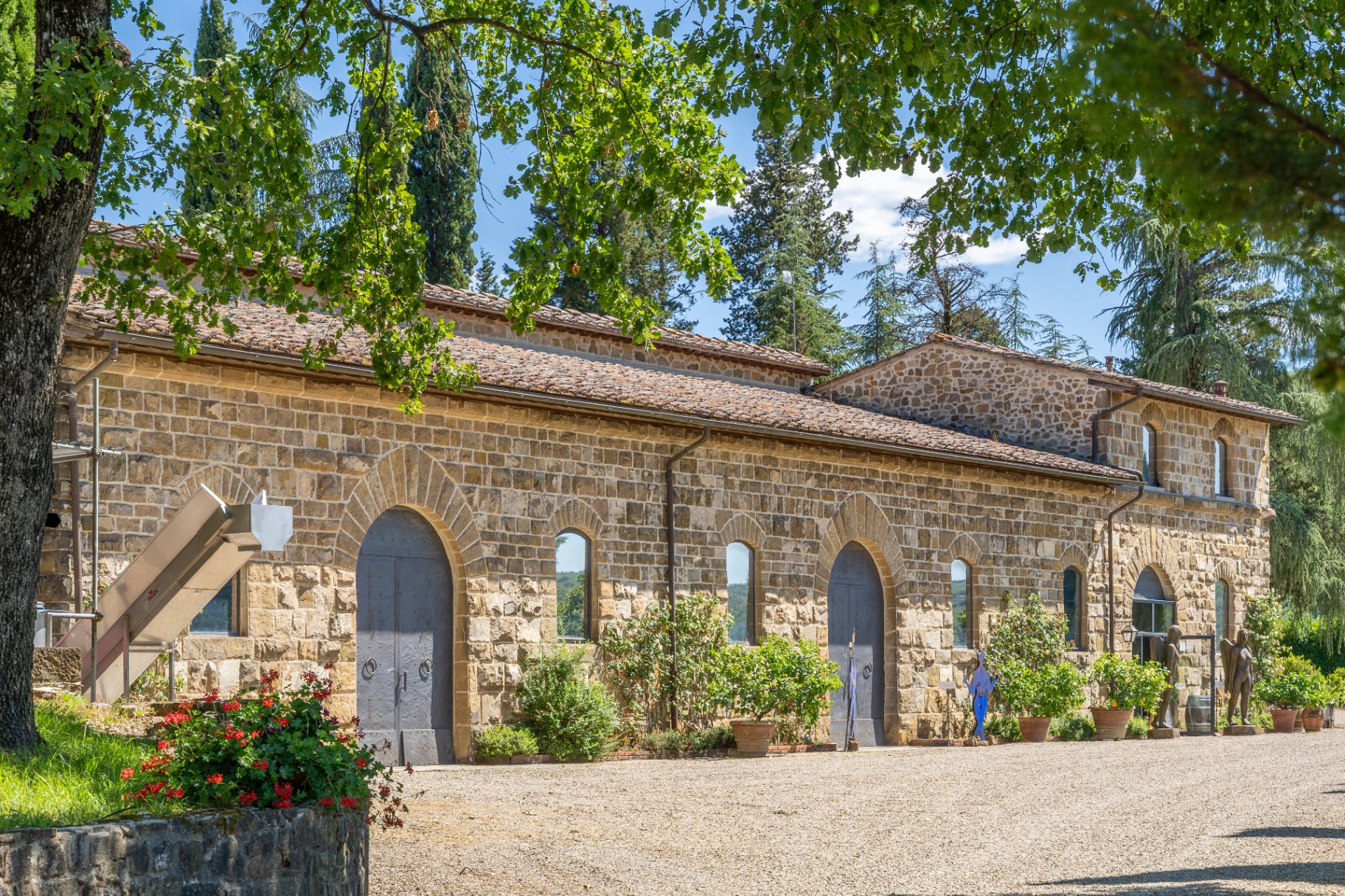 Stone winery building with arched doorways, terracotta roof and sculptures at the entrance