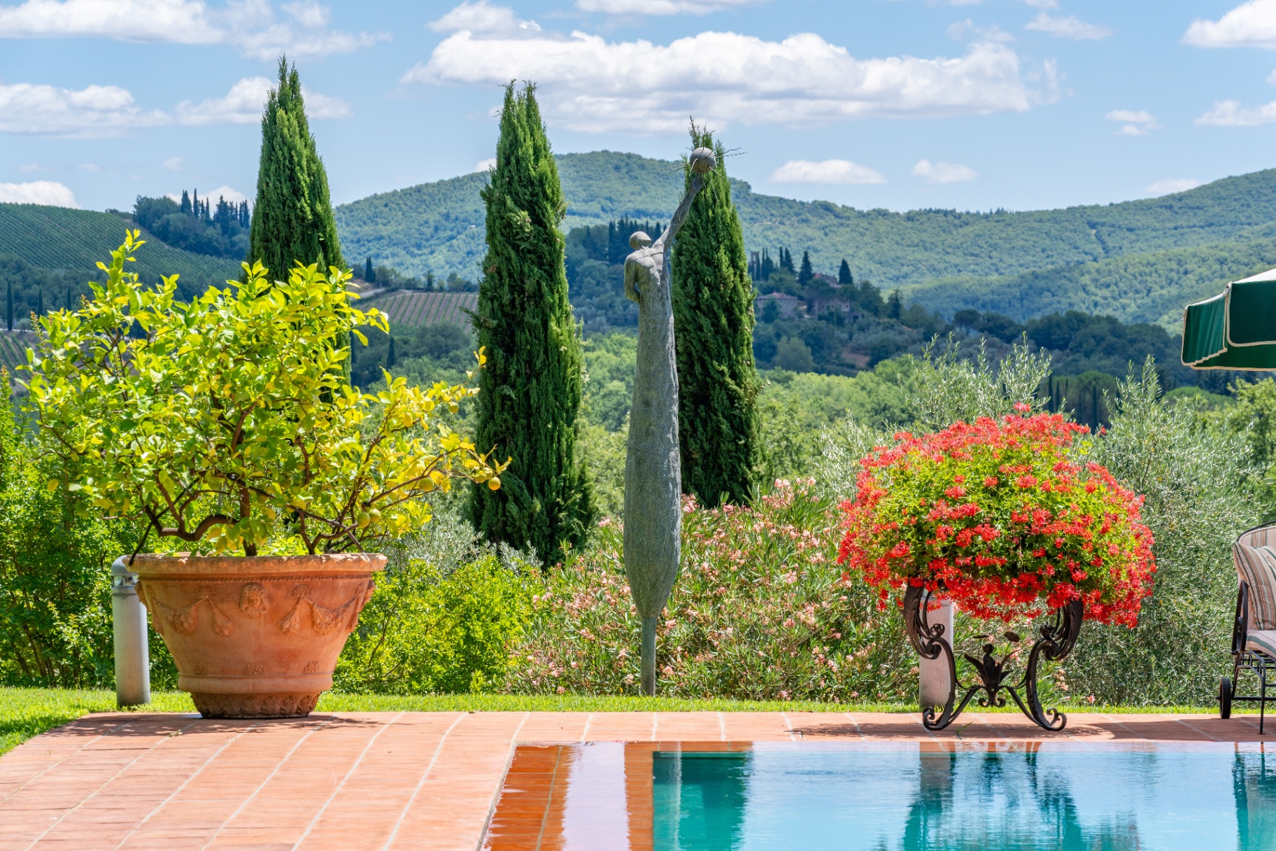 Bronze statue beside the pool with cypress trees and the Chianti hills beyond
