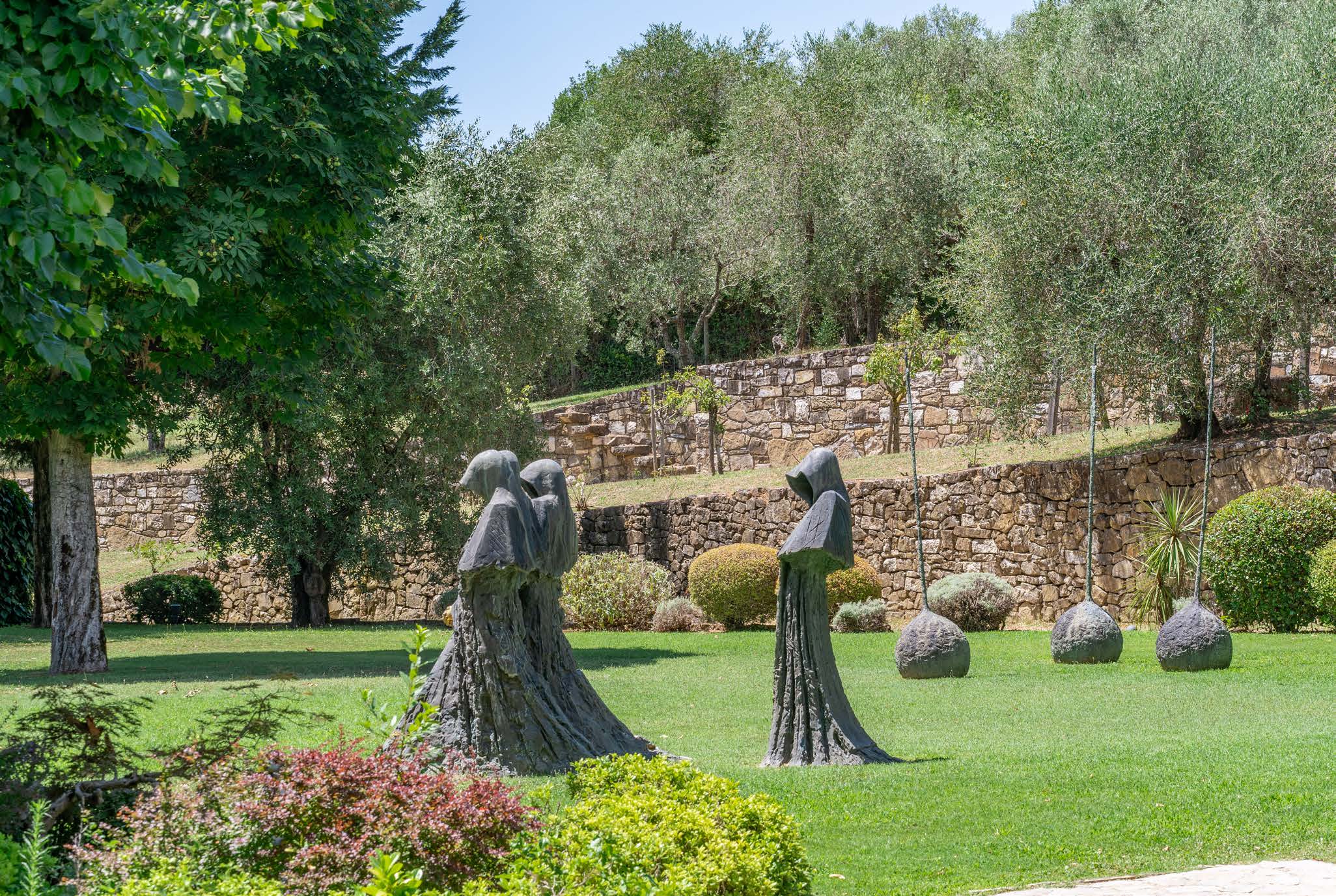Stone robed figures and spherical sculptures on a wide lawn