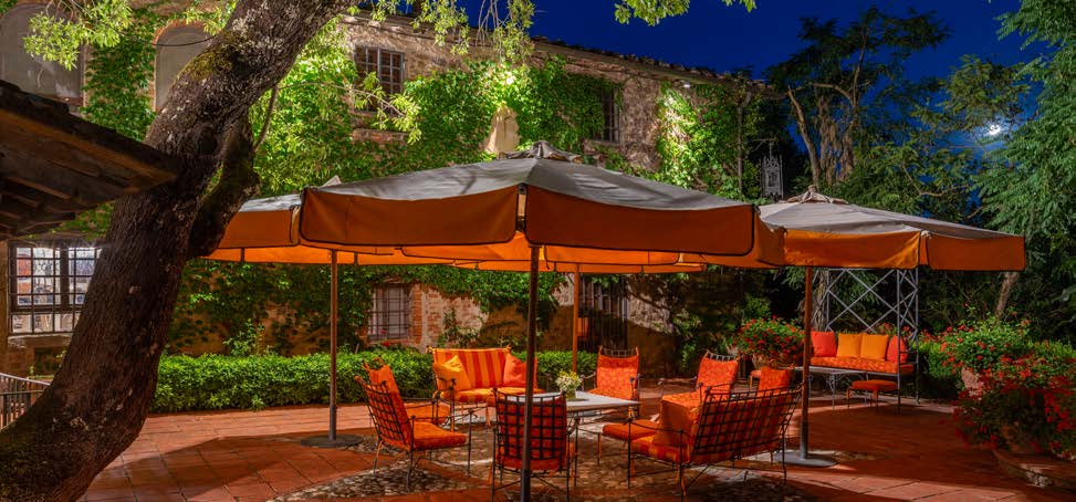 Outdoor dining lounge with orange umbrellas against a stone building