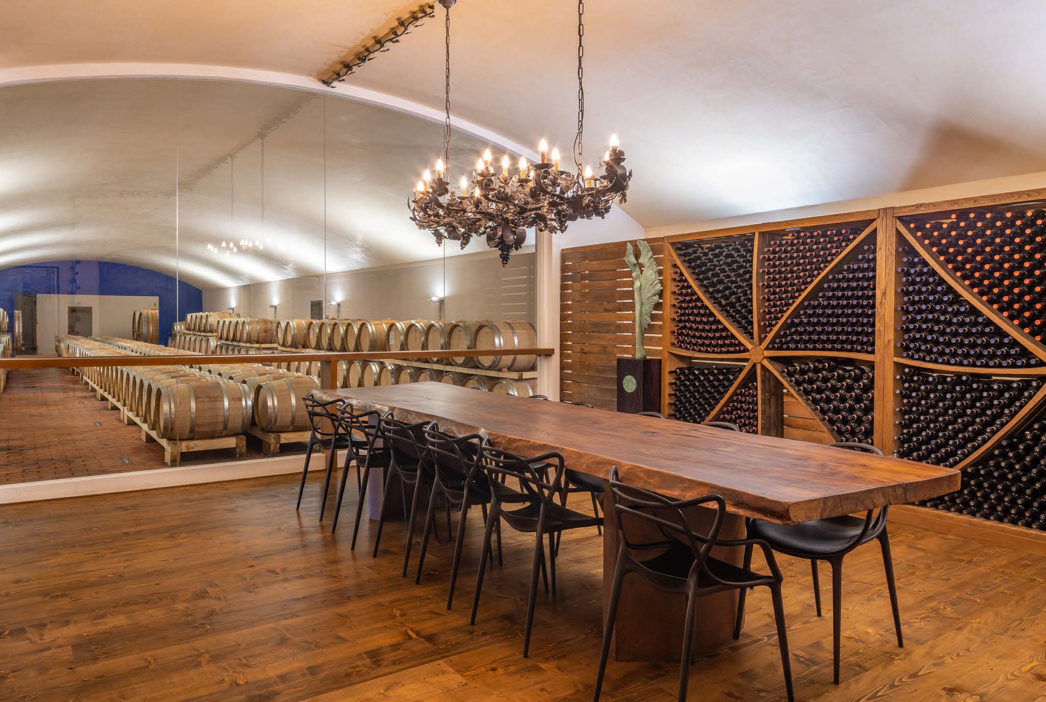 Tasting and barrel room with a long wooden table, chairs, barrels and wine racks