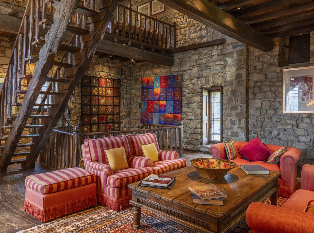 Interior of a rustic room with stone walls, wooden beams and colourful furniture